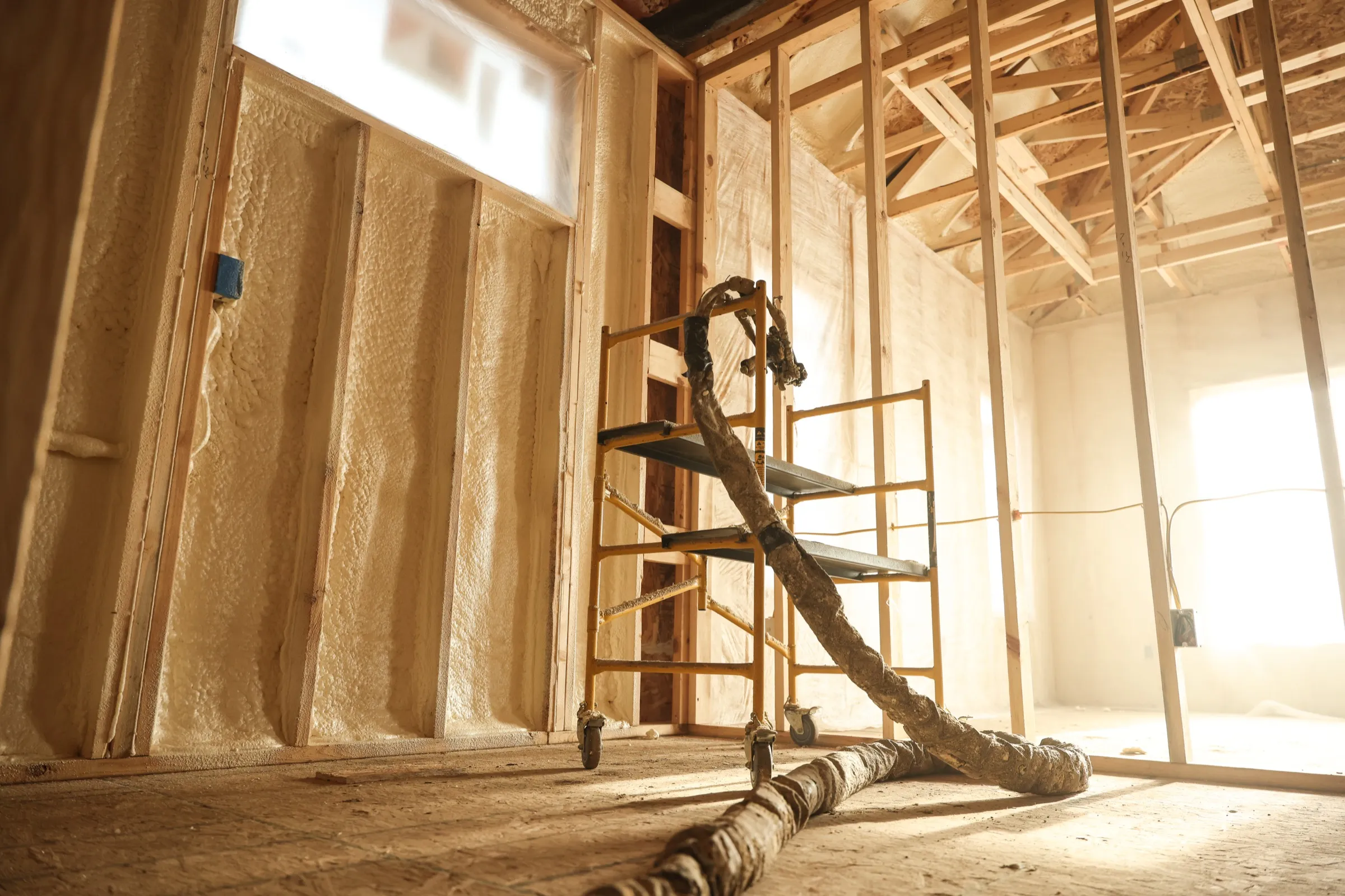 Installer spraying foam insulation with a pressure rig with professional equipment